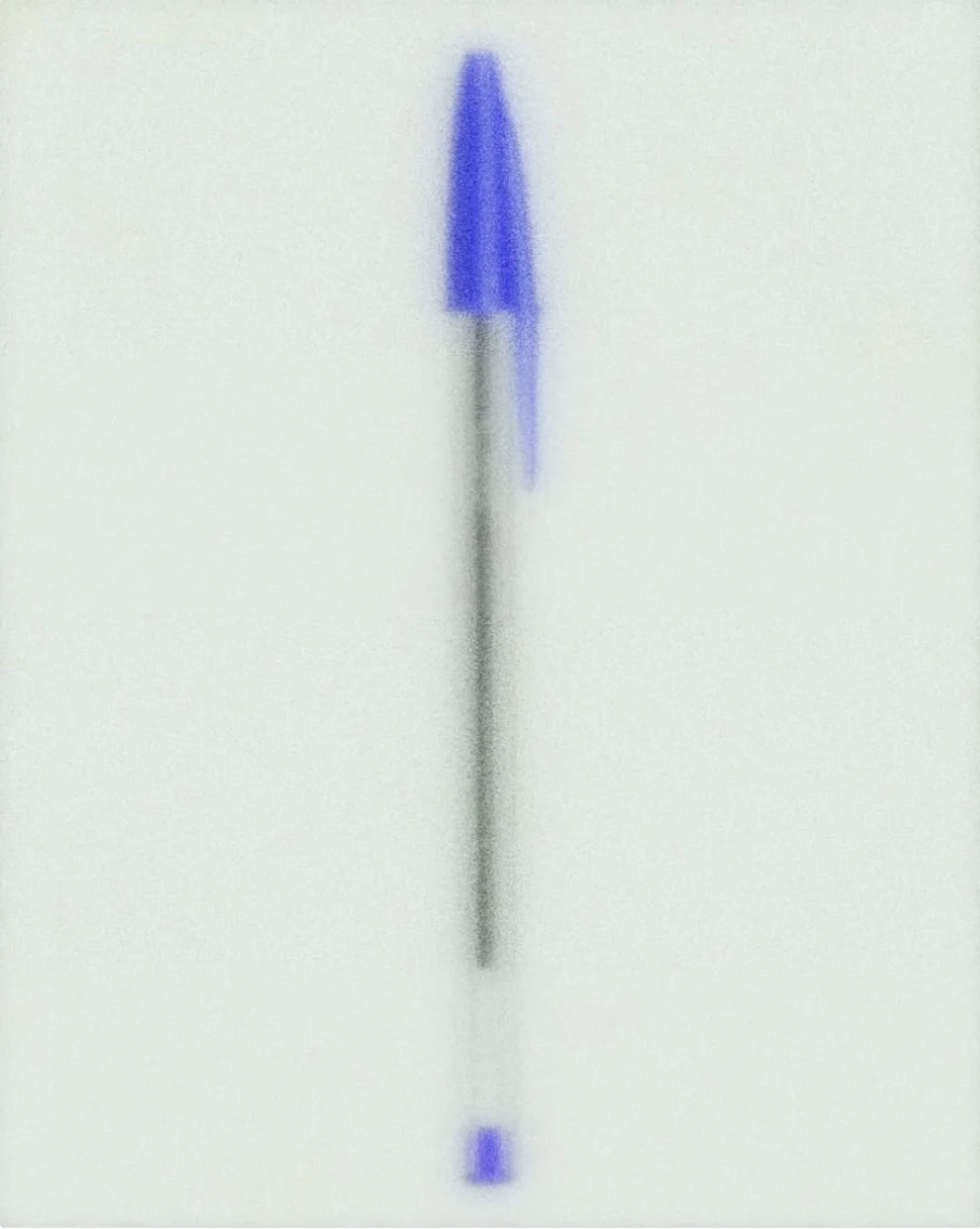 A blue ballpoint pen, softly out of focus, against a pale background.